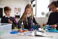 Three primary school children working together, following an instruction book and using construction blocks in a classroom, front Royalty Free Stock Photo