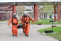 Three professional firefighter firefighters in orange protective fireproof suits, white helmets and gas masks carry the injured pe