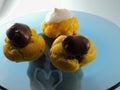 Three Profiterol with cream and chocolate  on a transparent plate Royalty Free Stock Photo
