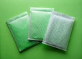 Three Protective Envelopes with Bubble Wrap on a Vibrant Green Background A Flat Lay for Packaging and Shipping Royalty Free Stock Photo