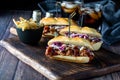 Three pulled pork sliders on a wooden board served with french fries and two cola beverages in behind. Royalty Free Stock Photo