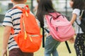 Three pupils of primary school go hand in hand. Boy and girl with school bags behind the back. Beginning of school lessons.