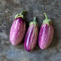 Three purple eggplants are displayed on a grey surface Royalty Free Stock Photo