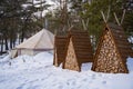 Three pyramidal sheds filled with dry wood in the middle of a snowy forest Royalty Free Stock Photo