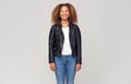 Three Quarter Length Studio Shot Of Happy Young Woman Wearing Leather Jacket Smiling At Camera