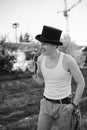 Three-quarter portrait of young man, wearing white top and black classic hat, holding sunglasses, smiling, laughing. Black and Royalty Free Stock Photo