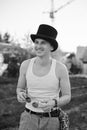 Three-quarter portrait of young man, wearing white top and black classic hat, holding sunglasses, smiling, laughing. Black and Royalty Free Stock Photo