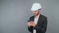 Three quarters of a business man in a business suit and white hard hat isolated on a gray surfi background in an