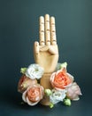 Three raised fingers of wooden hand with flowers on dark green background Royalty Free Stock Photo