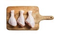 Three raw chicken legs with skin lying on a wooden cutting board. Fresh uncooked meat of poultry isolated on white background. Top Royalty Free Stock Photo