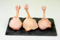 Three Raw chicken lollipops on a black stone plate isolated on white Royalty Free Stock Photo