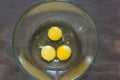 Three raw chicken yolks and whites in glass bowl on the wooden table Royalty Free Stock Photo