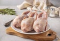 Three raw fresh quails on a white plate on a wooden board, Closeup, gray background Royalty Free Stock Photo