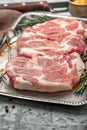 Three raw pork steaks on iron tray on light surface