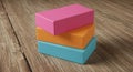 Three rectangular wooden blocks are stacked on a wooden surface. The blocks are
