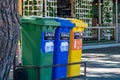 Three recycle containers for glass, plastic and paper on a city street