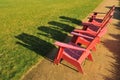 Three red adirondack chairs on a path