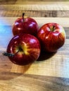 Three red organic apples on a wooden table Royalty Free Stock Photo