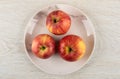 Three red apples in plate on wooden table. Top view Royalty Free Stock Photo