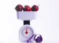 Three red apples on weighing scales with tape measure Royalty Free Stock Photo