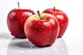 Three red apples on a white background with water drops