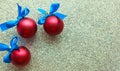 Three red balls with blue bows on silver background, top view. Merry Christmas and Happy New Year. Royalty Free Stock Photo