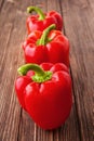 Three red bell peppers on a wooden background Royalty Free Stock Photo