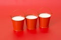 Three red buckets with milk on a red Royalty Free Stock Photo