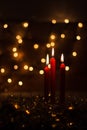 Three red candles with Christmas balls and dark background with lights Royalty Free Stock Photo