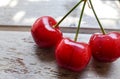 Three red cherries on wooden table n a sunny day Royalty Free Stock Photo