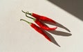 Three Red Chili Peppers on Beige Surface with Dramatic Sunlight Shadows Royalty Free Stock Photo