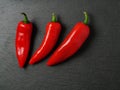 Three red chilly peppers on a dark slate plate, Top view Royalty Free Stock Photo