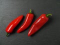 Three red chilly peppers on a dark slate plate, Top view Royalty Free Stock Photo