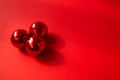 Three red Christmas balls on red background with contrasting shadows