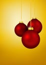 Three Red Christmas Balls hanging in front of Yellow Gold