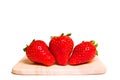 Three Red delicious strawberries full size placing together on wooden plate isolated Royalty Free Stock Photo