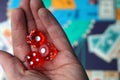 Three red dice cubes on the palm above the board game