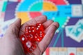 Three red dice cubes on the palm above the board game