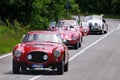 Three red Ferrari and a white Jaguar classic cars