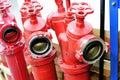 Three red fire hydrants with valves are in the warehouse