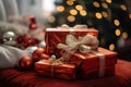 three red gift boxes sitting on a bed with a christmas tree in the background Royalty Free Stock Photo