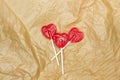 Three red heart shaped lollipops on a wrinkled brown paper Royalty Free Stock Photo