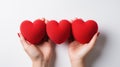 Three red heart-shaped objects held in female hands on a white background Royalty Free Stock Photo