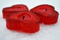 Three red hearts - candles on white snow, a gift for loved ones. Royalty Free Stock Photo