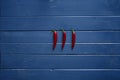 Three red hot chilis on blue wooden table