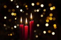 Three red lit candles with colorful bokeh background Royalty Free Stock Photo