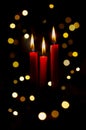 Three red lit candles with colorful bokeh background Royalty Free Stock Photo