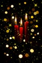 Three red lit candles with colorful bokeh background wiyh spots and stars Royalty Free Stock Photo