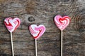 Three red lollipops in heart shape on wooden background
