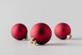 Three red matte Christmas balls on a seamless grey background